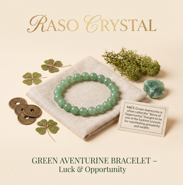 A green aventurine beaded bracelet displayed on a folded cream fabric cloth, surrounded by decorative props including four-leaf clovers, bronze coins, moss, a small polished crystal, and a fact card. The text 'RASO CRYSTAL' appears at the top and 'GREEN AVENTURINE BRACELET – Luck & Opportunity' appears at the bottom.